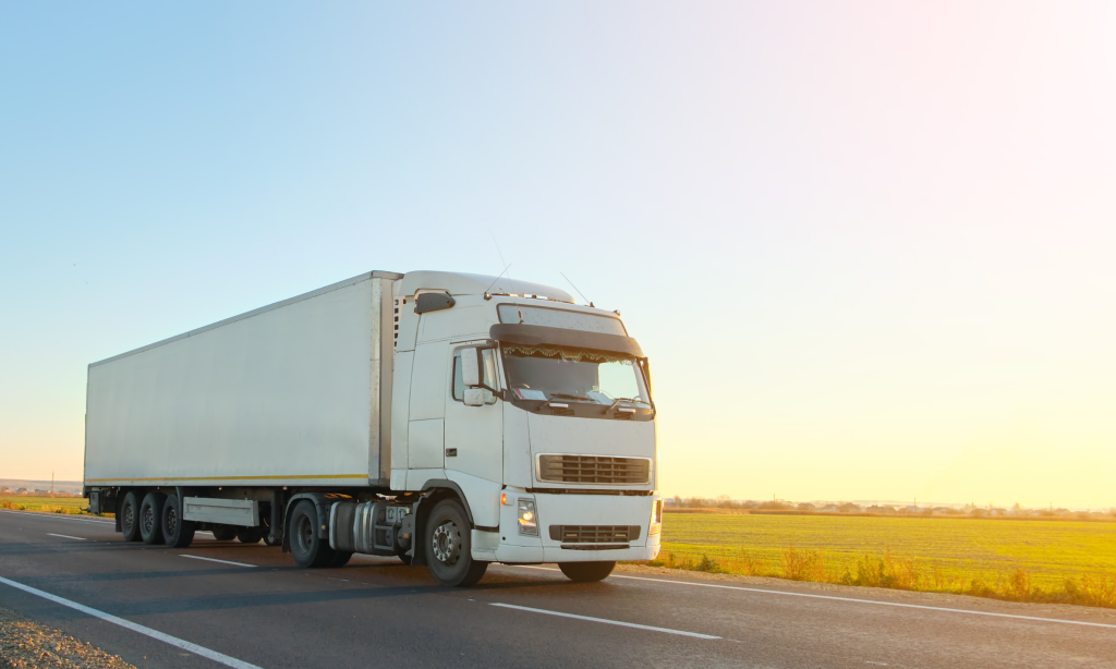 Moving truck driving across a road at sunset