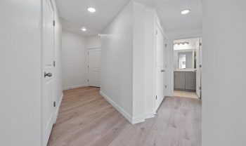 A hallway with white walls and hardwood floors. A hallway with white walls and hardwood floors.