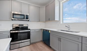A kitchen with gray cabinets and stainless steel appliances. A kitchen with gray cabinets and stainless steel appliances.