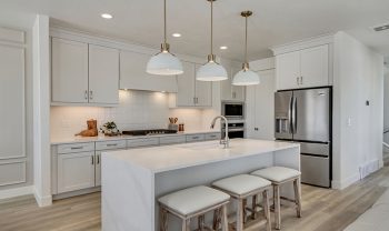 A white kitchen with a center island and stools. A white kitchen with a center island and stools.