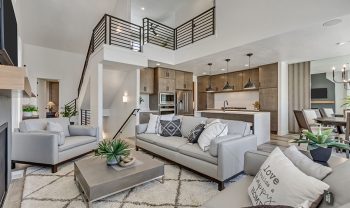 A modern living room with gray furniture and a staircase. A modern living room with gray furniture and a staircase.
