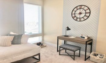 A bedroom with a desk and a clock on the wall. A bedroom with a desk and a clock on the wall.